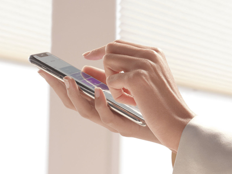 Hand using smartphone to control smart window blinds.