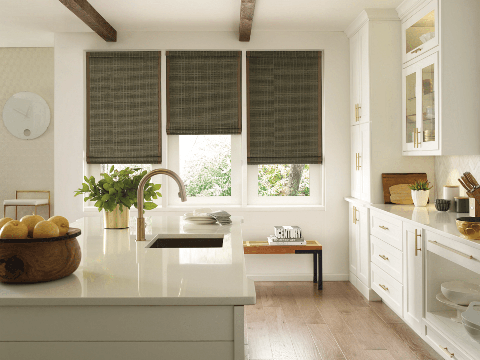 Woven wood shades enhance natural light in a Tucson kitchen with white cabinets & warm wood floors.